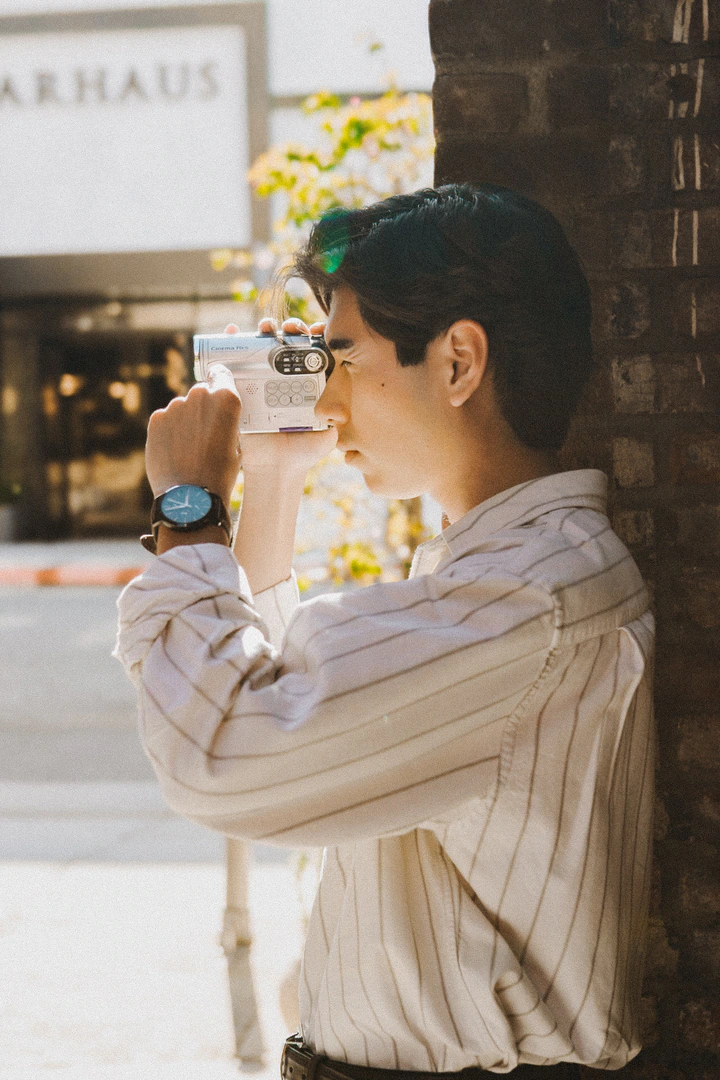 Kai filming with a handheld camcorder, seen in profile