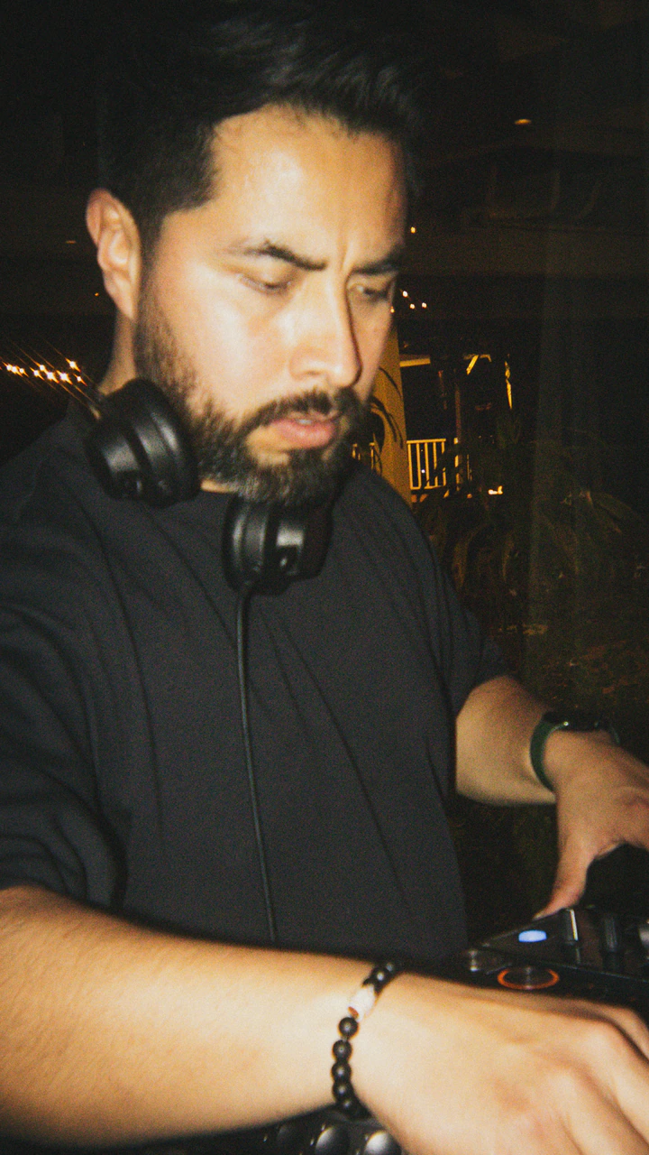 DJ with headphones around his neck working the decks at night