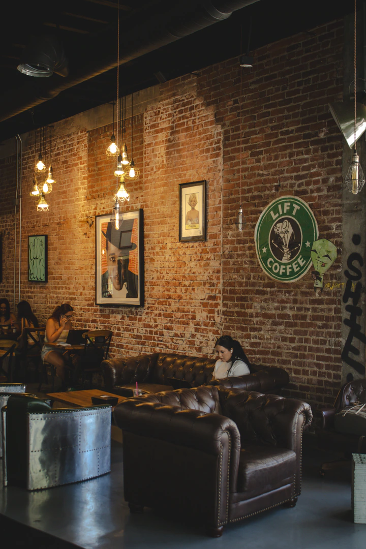 A customer on her laptop on a leather sofa below the Lift Coffee sign