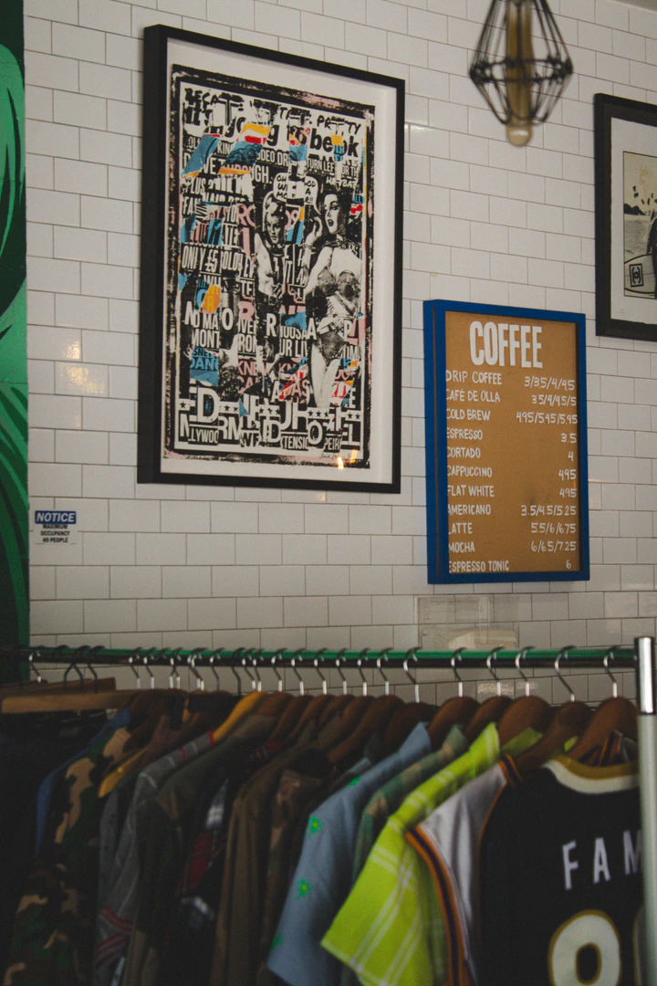 Coffee menu board and framed art on a white tile wall